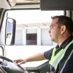 A profile photo of man wearing a high visibility vest sitting behind the wheel of a truck.